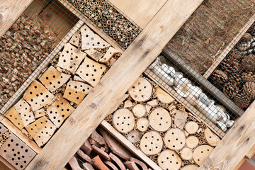 Detail of an insect hotel made of natural materials like wood, branches, bamboo sticks, pine cones...