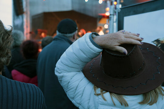 Eine Frau hält vor einer Konzertbühne ihren Hut fest