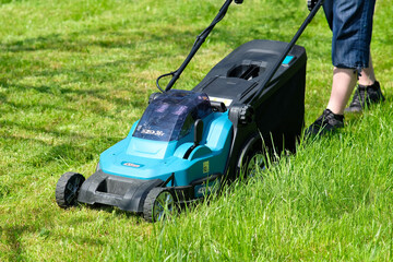 Fototapeta na wymiar Mowing the grass with a lawn mower. Maintenance garden