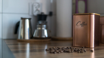 Photo of coffee beans and container. Classic coffee maker and grinder in the background. Kitchen - obrazy, fototapety, plakaty