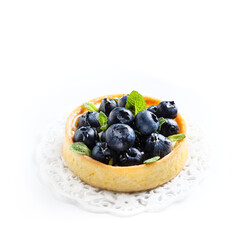 Blueberry tart with fresh mint leaves at white background, top view. French dessert with berries.