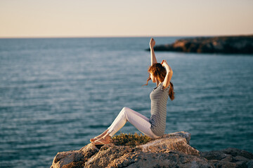 woman in striped t-shirt trousers and barefoot in the mountains near the sea