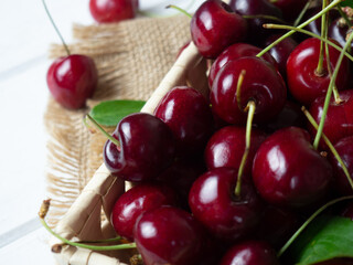 fresh cherries in a wicker basket on a white wooden table