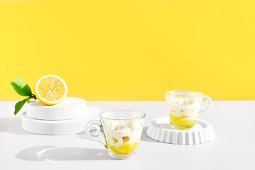 Lemon mousse or ice cream in a glass cups on yellow background. Traditional Italian recipe of lemon tiramisu or granita. Delicious summer dessert.