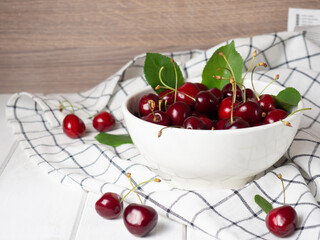 fresh cherries in a white bowl on a white wooden table