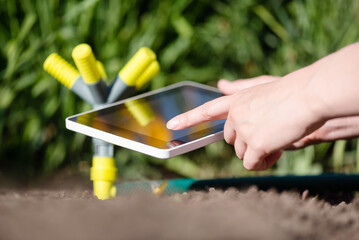 A gardener with a tablet using a smart garden application concept. Watering system. Electronic...