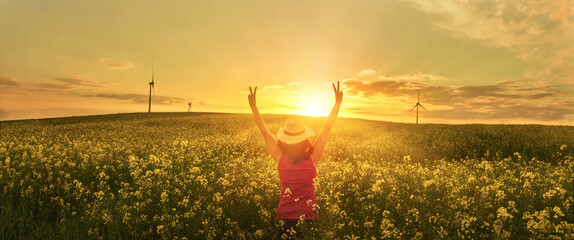 Happy woman giving the victory sign in the sunshine on sunset flower field