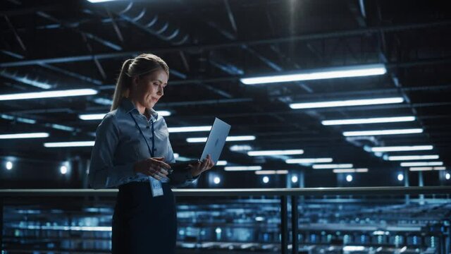 Data Center Female It Specialist Using Laptop. Server Farm Cloud Computing and Cyber Security Maintenance Administrator Working on Computer. Information Technology Professional. Wide Medium Shot