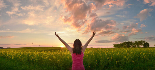 Happy woman enjoys beautiful sunset on flower field