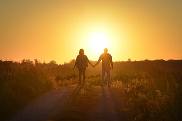 Young couple holding hands towards the Sun