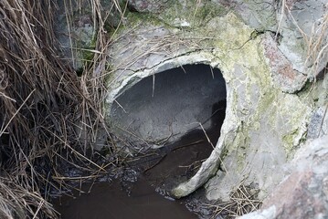 old gray pit with broken concrete sewer pipe in water