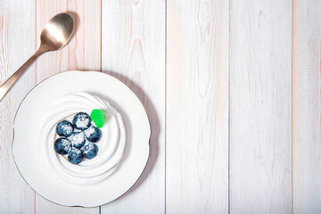 Top view on healthy vegan dessert anna pavlova on white wooden table with coffee spoon.