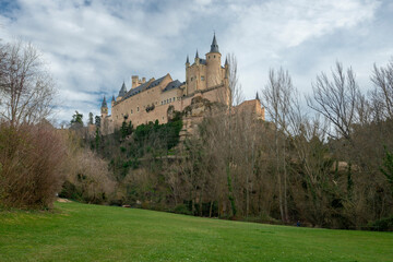 Fototapeta na wymiar Classic view of the beautiful Alcazar de Segovia in Castilla, Spain. With a green meadow in the foreground