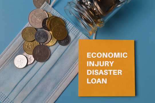 Top view of coins, face mask and paper note written with ECONOMIC INJURY DISASTER LOAN