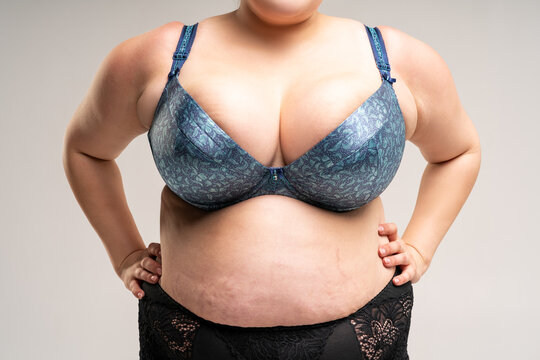Big natural breasts in blue bra, biggest boobs on gray background