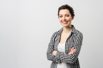 Business portrait of a young woman. A charming brunette looks at the camera, crossing her arms over her chest.