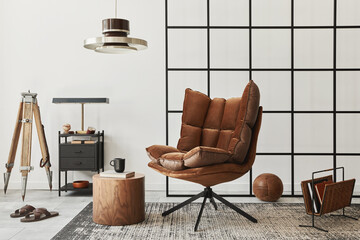 Modern interior of living room with design brown armchair, side table, pendatn lamp, loft wall, slippers, carpet, decoration and elegant personal accessories in home decor. Template.