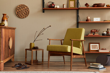 Stylish composition of retro living room interior with design armchair, wooden bookcase, coffee table, picture frames, plant, carpet, slippers, decoration and elegant accessories in home decor. 
