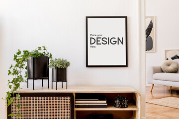 Stylish minimalistic living room interior with mock up poster frame, commode, plants in black pots...