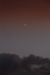 Moon in red sky with clouds at the bottom