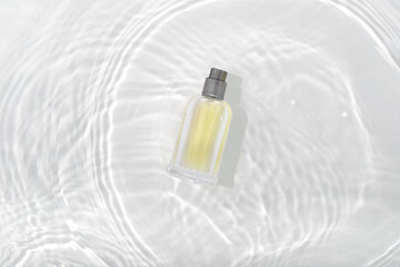 Cosmetics perfume bottle on splashing water surface with circles on white  background. Glass spray...