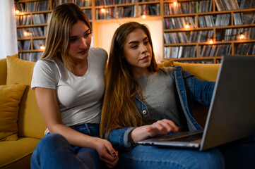 Young students using laptop while studying for their exam together at home