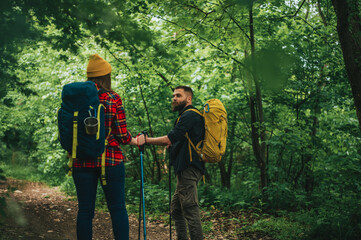 Naklejka premium A young couple of hikers using trekking poles and wearing backpacks