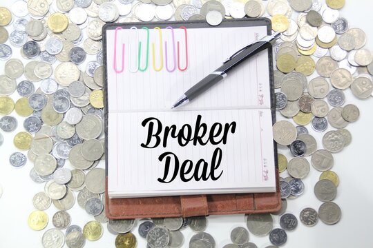 strewn coins, pens and notebooks with the word broker deal