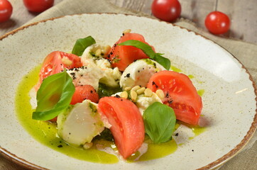 Caprese salad with mozzarella, tomato, basil and balsamic vinegar arranged on white plate closeup