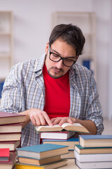 Young male student and too many books in the classroom