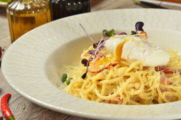 Pasta with with poached egg and cheese in white bowl. on wooden rustic background