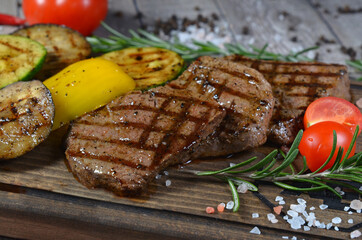 Meat steak with vegetables on wooden board closeup
