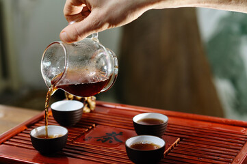 Fototapeta na wymiar Young girl pouring tea teapot close, Chinese tea ceremony.