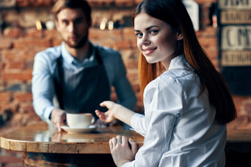 happy bartender serving a cup of coffee to a patient in a cafe drink brick wall interior