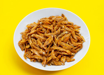 Fried Anchovies in white plate on yellow background.