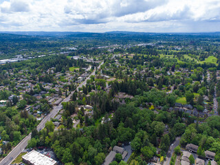 Obraz premium In the photo we see a city with a lot of greenery. We also see a lot of highways. Mountains can be seen in the distance. Blue sky with white clouds. View from above. Aerial photography.