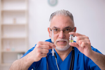 Old male doctor in vaccination concept