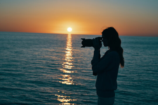 photographer with a camera at sunset near the sea