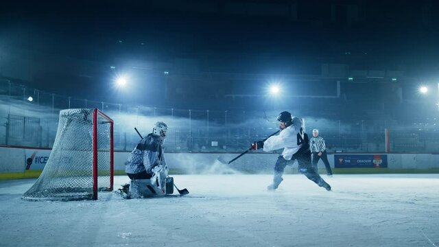 Ice Hockey Rink Arena: Goalie against Forward Player who Does Slapshot, Shoots Puck with Stick Scores Goal. Forwarder against Goaltender One on One. Cinematic Slow Motion Profile Static Wide Shot