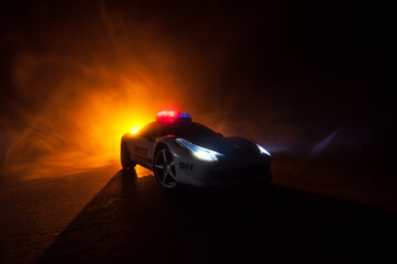 Plakat Police car chasing a car at night with fog background. 911 Emergency response police car speeding to scene of crime. Selective focus