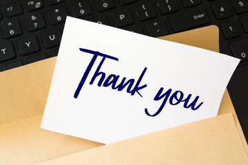 Thank You message, An embossed white card with brown envelope on keyboard with text Thank You