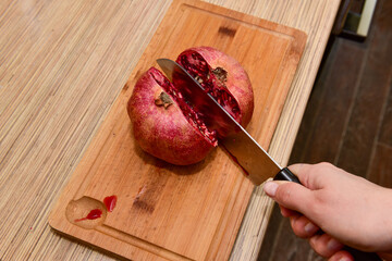 Female hands Cutting pomegranate in a kitchen. Close-up