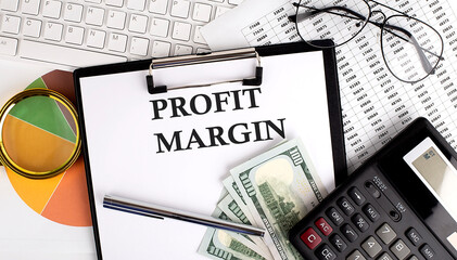 Text PROFIT MARGIN on Office desk table with keyboard, dollars,calculator ,supplies,analysis chart...