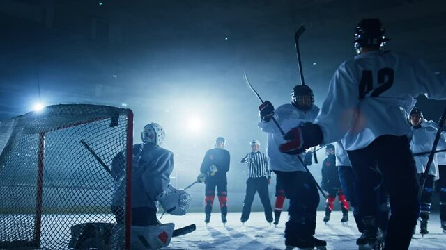 Ice Hockey Rink Arena: Goalie against Forward Player who Does Slapshot, Shots Puck with Stick and Scores Goal. Forwarder againstGoaltender.Team Celebrates. Cinematic Slow Motion Behind Goals Wide Shot