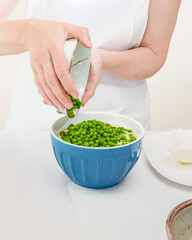 Green peas in a bowl. Step by step creamy pureed celery soup with fresh green peas recipe, woman hands, vertical banner