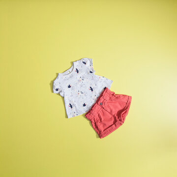 Baby fashion - set shirt and shorts for girls; photo on flat yellow background.