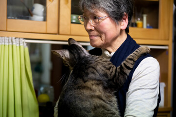 Portrait of an old Asian lady holding a brown patch cat in Japan.