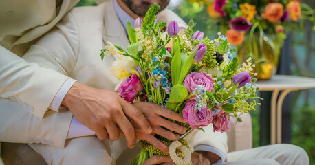 LGBTQ gay couple holding hand together with flowers bouquet in wedding ceremony