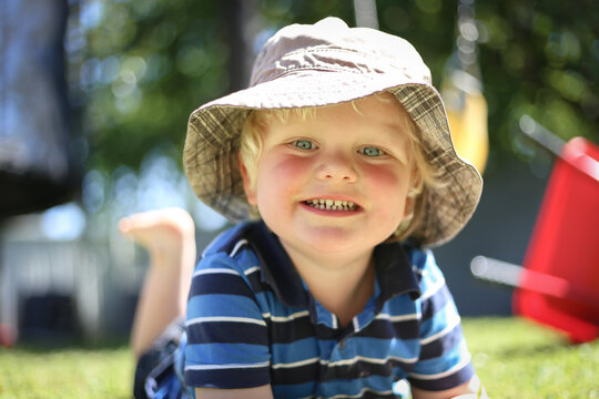 Cute little toddler boy wearing sun hat playing in backyard at home