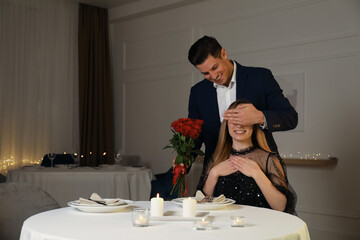 Man presenting roses to his beloved woman in restaurant at romantic dinner